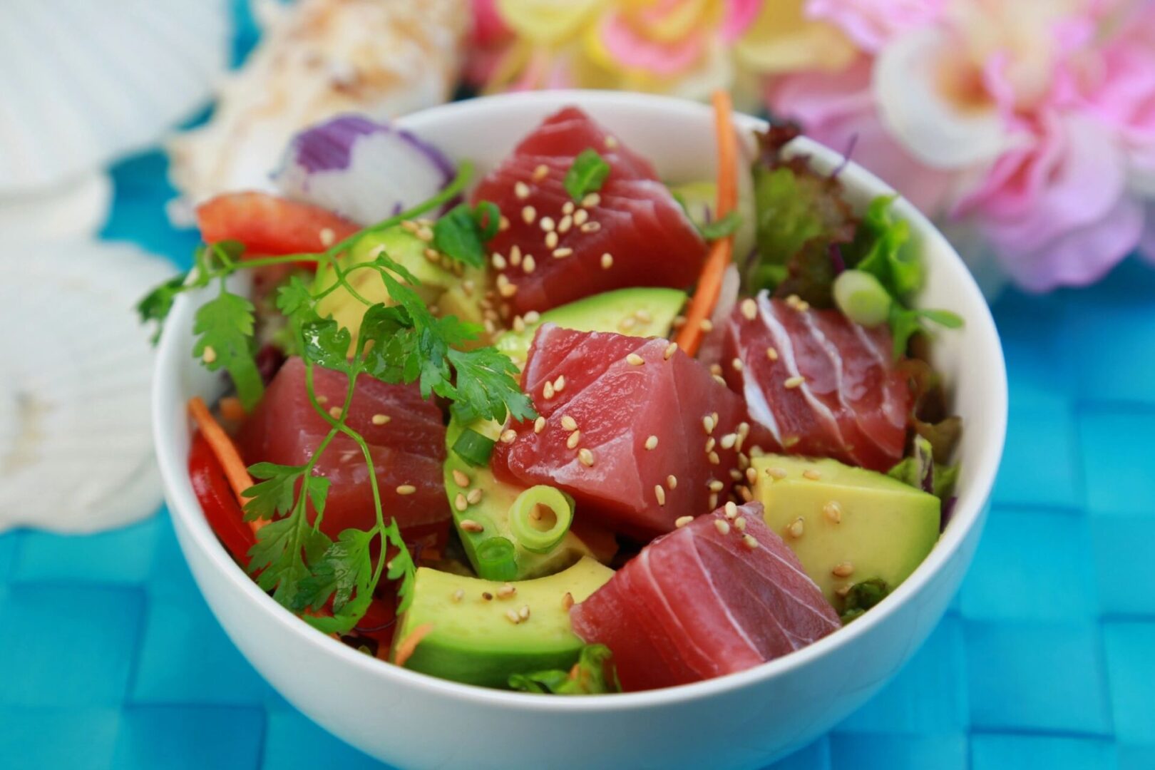 A bowl of food with tuna, avocado and sesame seeds.