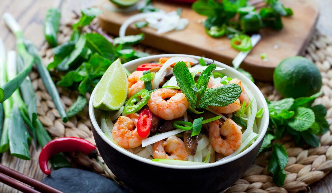 A bowl of shrimp salad with lime and cilantro.