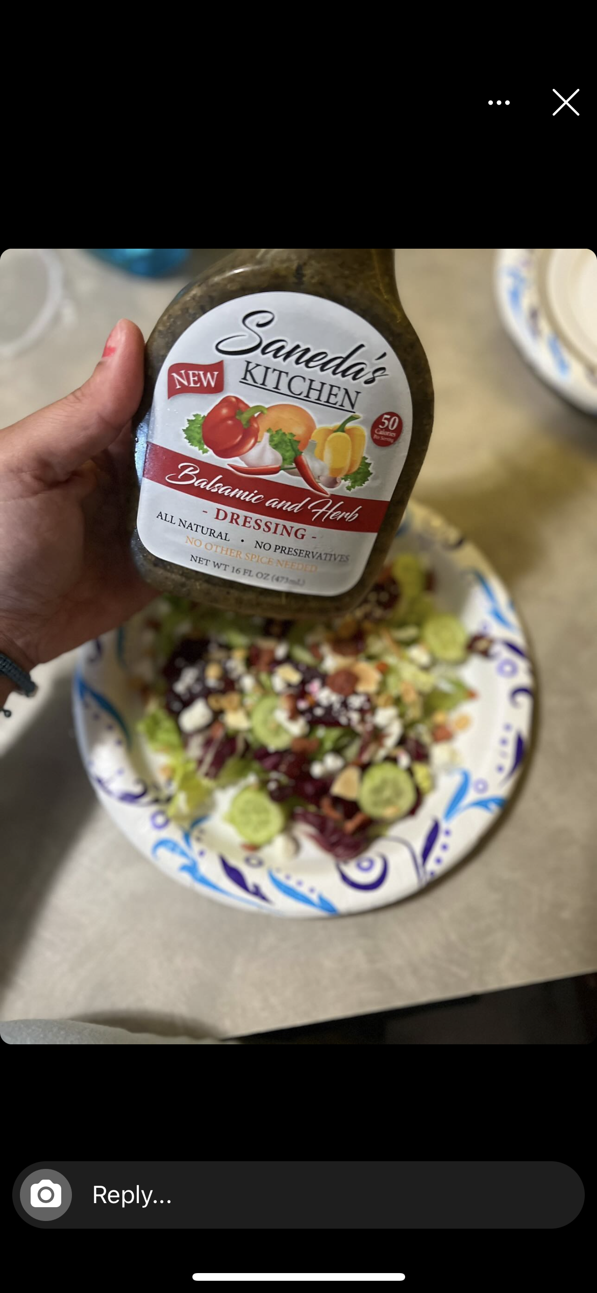 A person is pouring salad dressing on top of the salad.