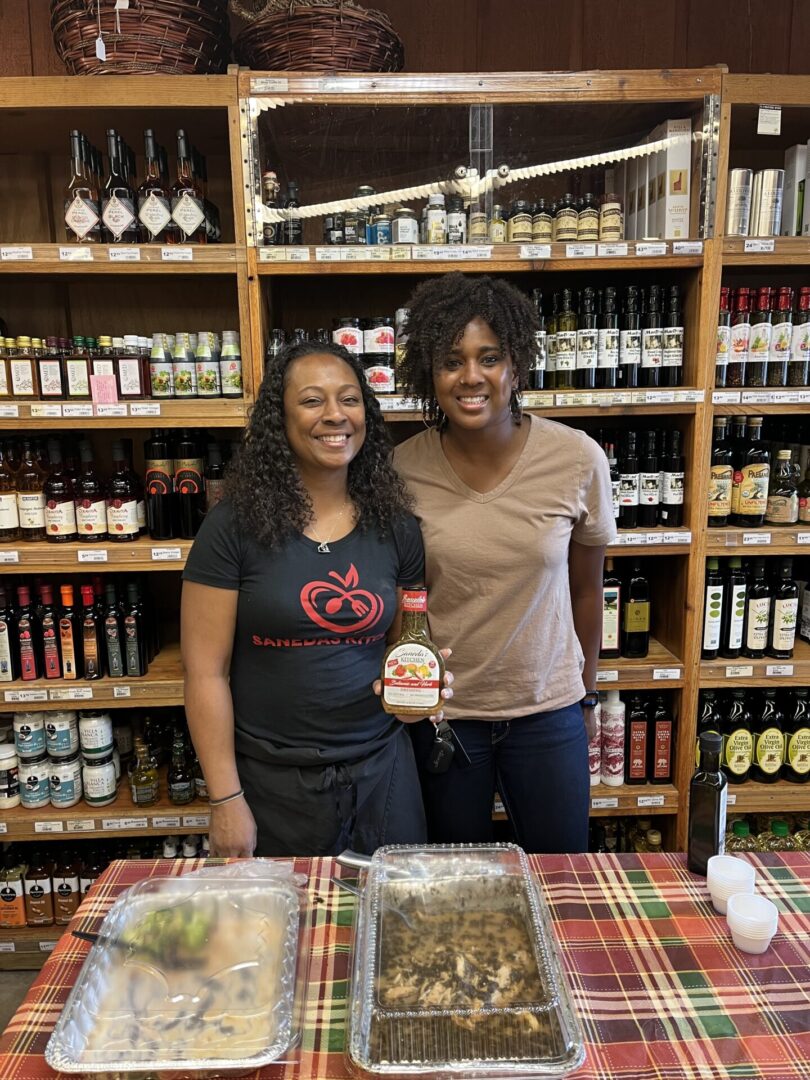 Two women standing in front of a table with food.