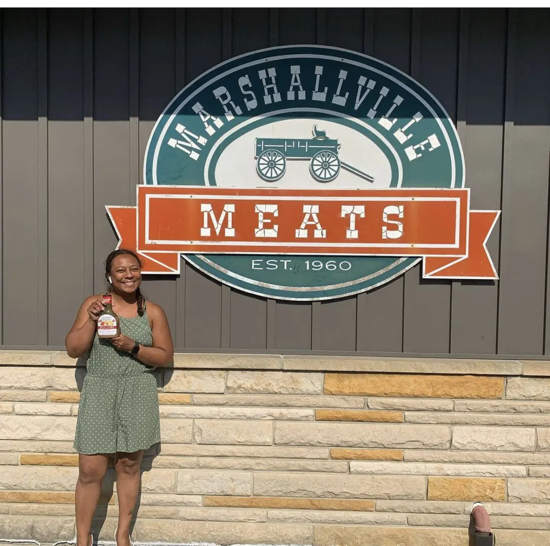 A person standing in front of a building with meat on the wall.