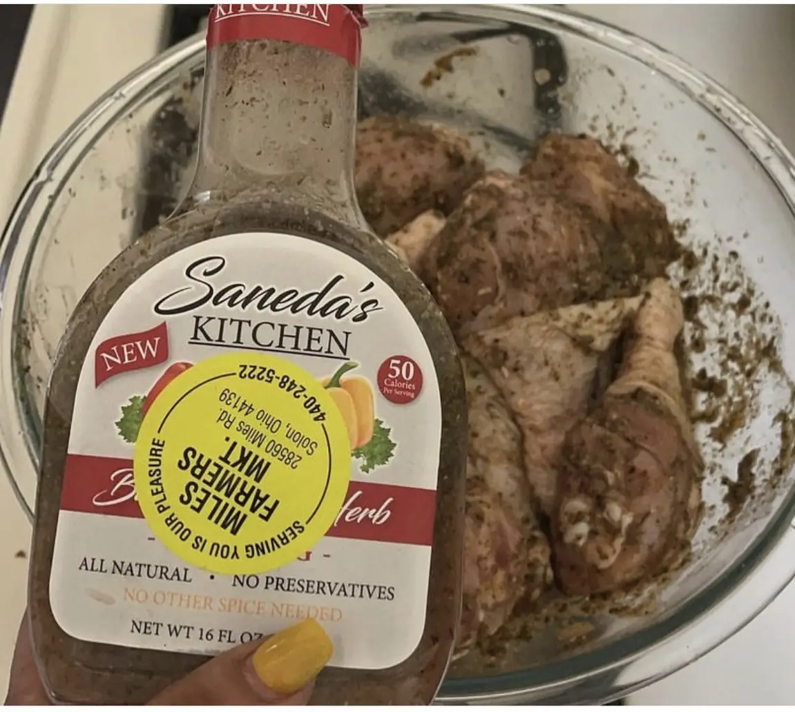 A bottle of sauce next to some meat in a bowl.