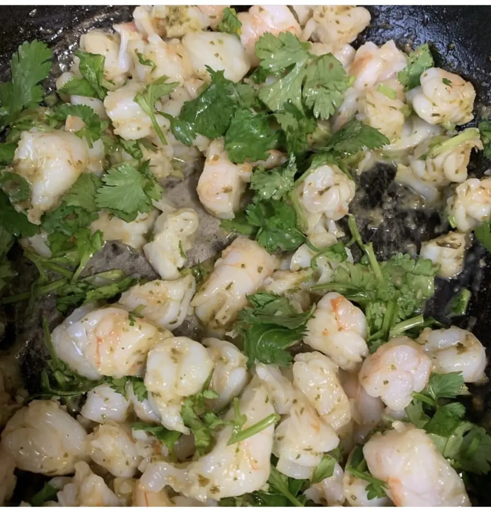 A pan of food with shrimp and cilantro.