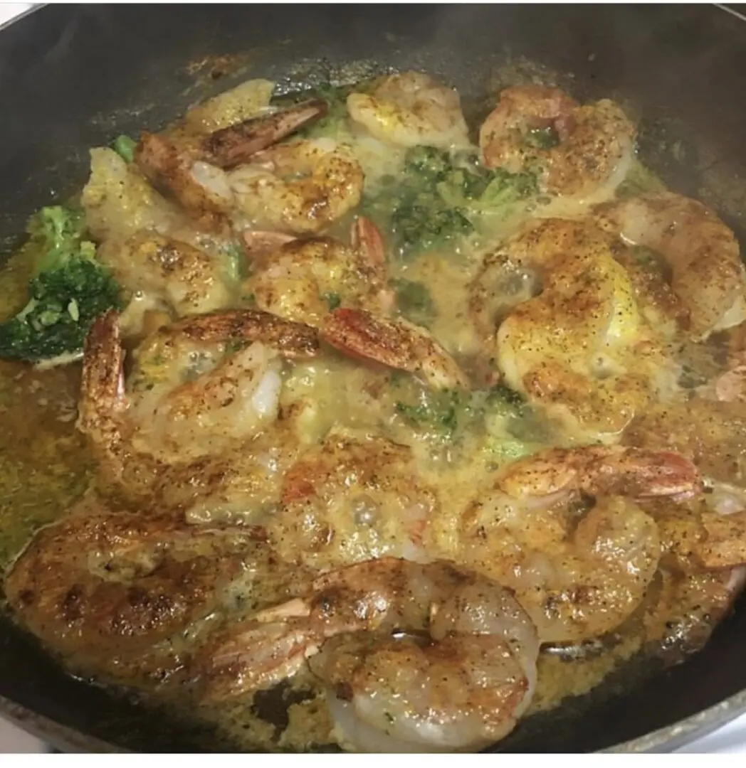 A pan of food with shrimp and broccoli.