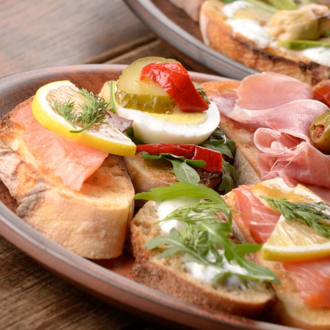 A plate of food with bread, ham and vegetables.